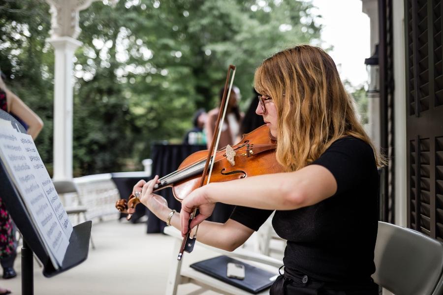 A student plays the violin while looking a sheet music. 